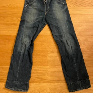 Blå jeansbyxor - Säljer ett par klassiska blå jeansbyxor med fem fickor och knappgylf. Byxorna är köpta på plick tidigare. Står ingen storlek men skulle säga att de är i storlek S/M.