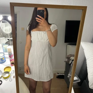 Vit klänning med puffärmar - Charmig vit klänning med puffiga kortärmar och en smickrande passform. Perfekt för sommarens varma dagar. Den har en söt, texturerad yta och en bekväm längd som slutar ovanför knäna.