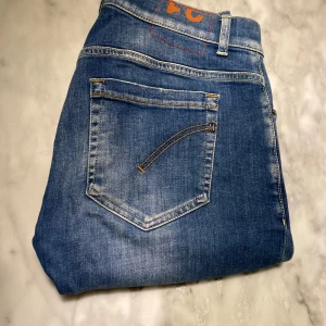 Blå Dondup george jeans W31 med slitningar  - Skick: 9/10. Jeansen har inga defekter och är i mycket gott skick. Slitningarna är fabriksgjorda och inga defekter. Blå färg och W31. Om du är osäker på om det kommer att passa kan du alltid fråga om mått! 