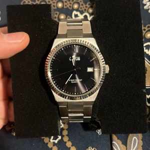 Lotus Klocka  - Klockan är gjort av stainless steel, den är även water resistant, klockan är 6 månader gammal som ni kan se på kvittot, inga grova skador förutom lite småskrapor som är på armlänken, kvittot följer med även extra länkar ifall klockan är för liten, nypriss är 1000 men jag lägger mitt pris på 700.
