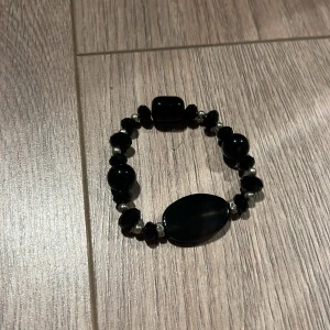Svart armband med pärlor - Snyggt svart armband med oregelbundna pärlor i olika storlekar. Perfekt för att ge en elegant touch till din outfit. Elastiskt band för enkel passform.