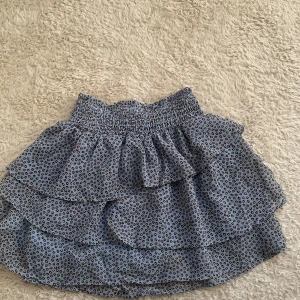 Blå leopardmönstrad kjol från H&M - Säljer en söt blå kjol från H&M med leopardmönster. Kjolen har en volangdetalj och en elastisk midja för en bekväm passform. Perfekt för en trendig look!