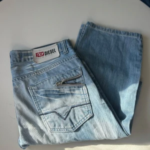 Ljusblå jeans från Diesel - Snygga ljusblå jeans från Diesel med klassisk femficksdesign och en liten dragkedja på bakfickan. Perfekta för en avslappnad stil. Märkesdetaljer syns tydligt på både fram- och baksidan.