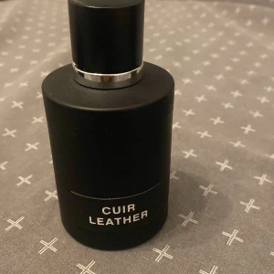 Cuir Leather parfym - Säljer en elegant parfymflaska med texten 'Cuir Leather'. Perfekt för den som gillar en sofistikerad doft. Luktar identiskt med tom Ford ombre leather. Ca 90ml kvar i flaskan.