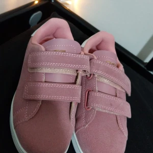 Rosa sneakers från Oxide - Säljer ett par rosa sneakers från Oxide i modellen Melbourne JR Dusty Rose. Skorna har kardborreband för enkel på- och avtagning och en vit sula. Perfekta för en avslappnad stil.