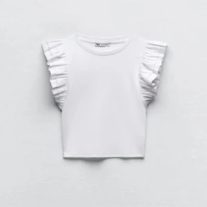 Vit topp med volangärmar från Zara - Säljer en söt vit topp från Zara med volangdetaljer på ärmarna. Toppen är ärmlös och har en croppad passform, perfekt för varmare dagar. Enkel och stilren design som passar till det mesta. Perfekt för att skapa en chic look!