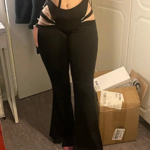 Svarta byxor med glittriga detaljer - Snygga svarta byxor med hög midja och glittriga detaljer vid höfterna. Byxorna har en tight passform upptill och vida ben. Perfekta för en kväll ute med vänner!