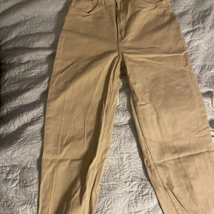 Beige byxor - Snygga beige byxor i en klassisk stil. De har en rak passform och är perfekta för en avslappnad look. Byxorna har fickor både fram och bak.