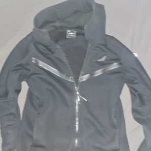 Svart nike tech - Säljer en fin svart nike tech hoodie. Använd minst 5-10 gånger 