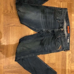 Replay - Snygga mörkblå jeans från Replay med klassisk femficksdesign och subtila slitningar. De har en normal passform och är perfekta för en avslappnad stil. Märkeslogga på bakfickan ger en extra touch. Fråga om du har frågor