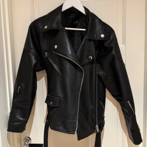 Svart skinnjacka med dragkedja - Svart skinnjacka i storlek xs men är oversized så är mer som en s/m. Den är i bra skick men har ett litet hål på insidan vid kragen. Hör av dig om du har frågor 😊
