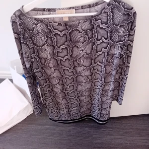 Ormmönstrad klänning från Michael kors  - Snygg äkta ormmönstrad klänning från Michael kors  i svart och grått. Klänningen har långa ärmar och en rund halsringning..