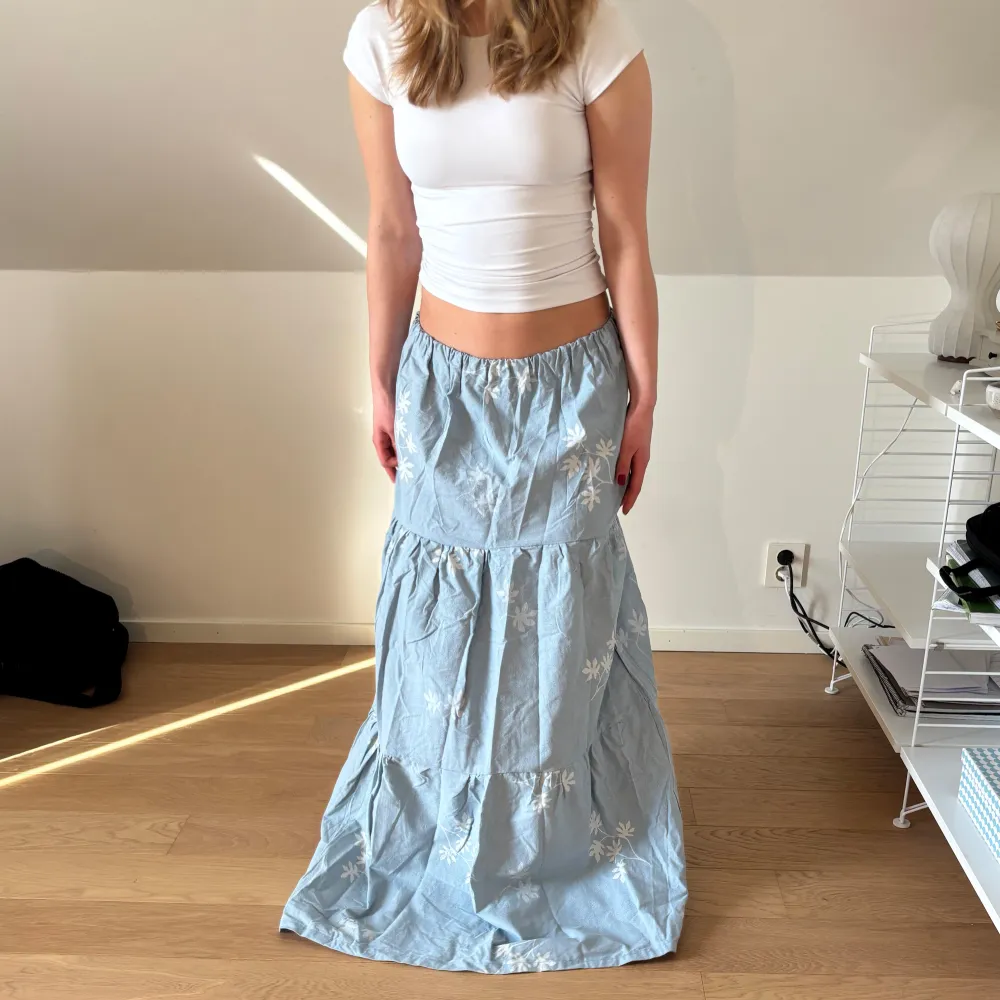 Säljer en ljusblå egensydd långkjol med ett vackert blommönster.💞Perfekt till våren och sommaren! Personen på bilden är 162 cm och kjolen är för lång för mig, men kan även sy upp kjolarna.🫶🏼passar xs-m pga bandet i midjan. Tyget är gjort av bummul. Ställ gärna frågor och pris kan diskuteras. 🩷🫶🏼🎀. Hameet.