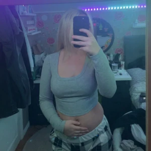 Grå croppad långärmad topp - Säljer en stilren grå croppad topp med långa ärmar. Perfekt för en avslappnad look. Toppen har en enkel design som gör den lätt att matcha med olika outfits.