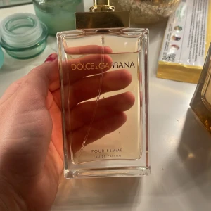 Dolce & Gabbana Pour Femme Eau de Parfum - Elegant och feminin parfym från Dolce & Gabbana i en stilren, rektangulär glasflaska med guldlock. Doften är klassisk och tidlös, perfekt för den som vill ha en sofistikerad touch.