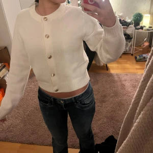 Vit kofta med knappar - Vit kofta med guld knappar från H&M i storlek S. Den är helt oanvänd. Säljer på grund av att den inte kommer till någon användning. Men verkligen super fin! Köpt för 299kr.