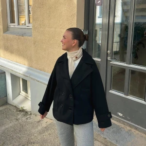 Design By Si Svart kappa - LÅNADE BILDER. Snygg svart kappa med dubbelknäppning och bred krage. Knappt tecken på användning på grund av att den är för liten. Nypris 760 kr.