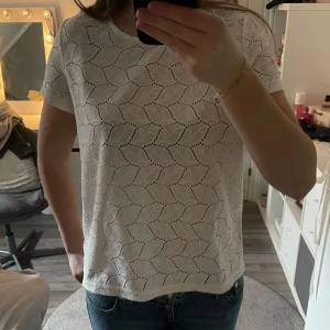 Vit blus med mönster - Säljer en söt vit blus med korta ärmar och ett fint hålmönster. Liten i storleken.