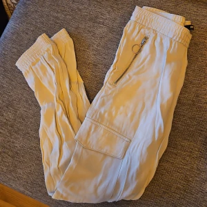 Beige byxor med dragkedja - Snygga beige byxor med elastisk midja och cool dragkedjedetalj. Perfekta för en avslappnad stil med en touch av edge.