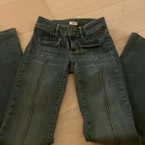 Blå bootcut jeans från Nelly - Snygga blå bootcut jeans från Nelly med låg midja och unika fickdetaljer fram. Väldigt bra skick och använt fåtal gånger.