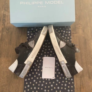 Svarta sneakers från Philippe Model - Snygga svarta sneakers från Philippe Model med vita detaljer och snörning. Skorna har en klassisk design med en robust sula och är perfekta för en stilren look. Levereras i originalkartong. Storlek 44 passar även 43. Köpta i julas men vill ha nått nytt nu. Jätte bra skick och tags medföljer 