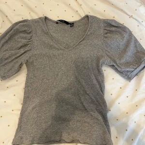 Fin topp - Superfin grå topp från vero Moda i storlek S. Den har puffiga, veckade ärmar. Det mörkare partiet på första bilden är skuggan av mig som fotar! Den är aldrig använd.  Pris kan diskuteras 💕