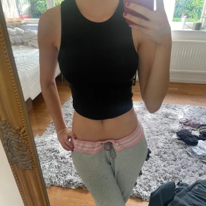 Svart ärmlös croppad topp - Säljer en svart croppad topp som är perfekt för sommaren. Den är tight och sitter snyggt på kroppen. Passar både till vardags och fest!