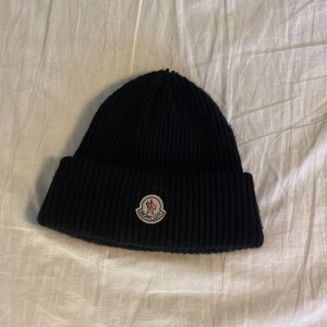 Moncler mössa - Moncler mössa använd fåtal gånger i mycket bra skick! sitter perfekt inga hål på Mössan, nypris 2200kr. Pris kan diskuteras vid snabb affär. Hör vi av er vid frågor!