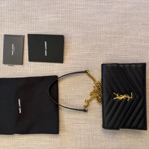 Svart axelväska från Saint Laurent - Säljer nu min Ysl väska ”Cassandre envelope chain wallet”.  Köpte den 2019 i Paris, endast använd vid fåtal tillfällen.   Kvitto, äkhetsbevis samt dustbag följer med.  Priset går att diakutera vid snabb affär
