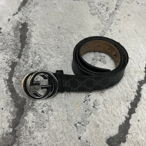 Svart bälte från Gucci - Snyggt svart bälte från Gucci med det klassiska GG-mönstret och en stilren silverfärgad GG spänne. Perfekt för att ge en lyxig touch till din outfit. Tillverkat i Italien med högkvalitativt material.