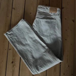 Grå jeans från Weekday - Säljer ett par gråa jeans från Weekday i modellen Arrow Low Straight. De har en klassisk femficksdesign och är tillverkade i ett bekvämt denimtyg. Perfekta för en avslappnad stil. Har dock ett litet hål vid midjan men det syns inte jättemycket. Har använts ca 3 ggr 