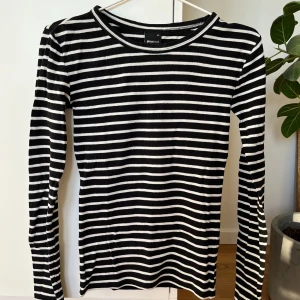 Svartvit randig tröja från Gina Tricot - Säljer en stilren svartvit randig tröja från Gina Tricot. Tröjan har långa ärmar och en klassisk rund halsringning. Perfekt för en avslappnad look.