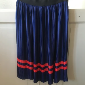 Blå plisserad kjol från Saint Tropez - Snygg blå plisserad kjol från Saint Tropez med röda ränder längst ner. Perfekt för en stilren look. Resår i midjan för bekväm passform.