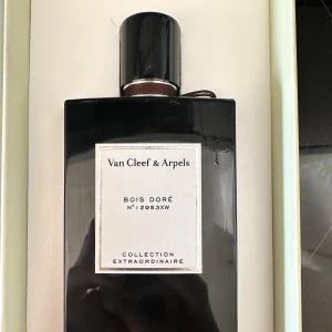 Bois Doré från Van Cleef & Arpels - Elegant parfymflaska från Van Cleef & Arpels, Bois Doré, ur Collection Extraordinaire. Flaskan är svart med en stilren etikett och ett matchande svart lock. Perfekt för den som söker en lyxig doftupplevelse. Flaskan är svart så de är svårt att se exakt vad den innehåller men den är fåtal gånger använd endast. Passar unisex.