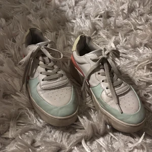 Flerfärgade sneakers från Attitude - Snygga sneakers i vitt med detaljer i mintgrön och korall från Attitude. Skorna har snörning och en bekväm passform. Perfekta nu inför våren!