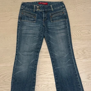 Low waist jeans  - Snygga blå vintage jeansbyxor från Kenvelo  med bootcut-stil. Byxorna har en klassisk femficksdesign och en knappgylf. Perfekta för en avslappnad look.