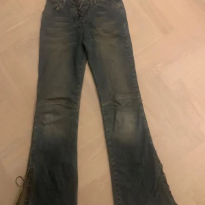 Blå jeans med snörning från Lamici - Snygga blå jeans från Lamici med unik snörning både fram och längs benen. Jeansen är bootcut och lågmidjade. Innebenslängd: 80cm, midja rakt över: 35 cm. Skriv för fler bilder eller frågor💕