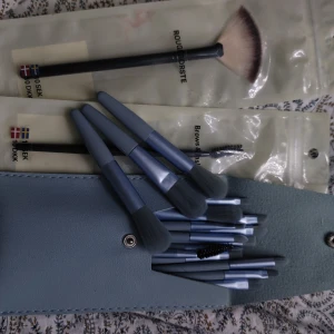 Set med sminkborstar i blått fodral - Ett set med flera sminkborstar i olika storlekar och former, inklusive en rougeborste och en ögonbrynsborste. Borstarna har blå handtag och kommer i ett snyggt blått fodral med knappstängning.