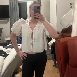 Vit blus med puffärmar - Supersöt vit blus med knytning i fram. Aldrig använd lappen finns kvar