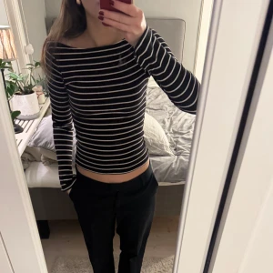 Svart och vit randig tröja - Säljer en stilren svart och vit randig tröja med långa ärmar. Tröjan har en tight passform och är perfekt för en avslappnad look. Är en tröja åt mer off shoulders och har slits vid ärmarna. 