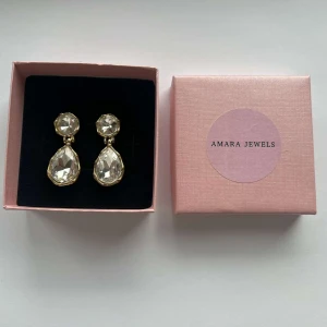 Guldörhängen med stora kristaller  - Eleganta guldörhängen med stora, klara kristaller. Örhängena har en rund kristall upptill och en droppformad kristall nedtill🩷