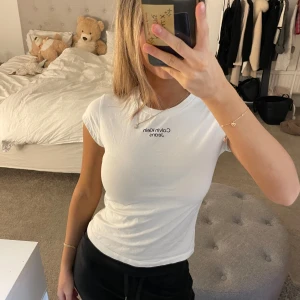 Vit t-shirt från Calvin Klein Jeans - Säljer en stilren vit t-shirt från Calvin Klein Jeans. Den har en klassisk rund hals och korta ärmar med logotypen tryckt på bröstet. Perfekt för en casual look. Använt ett få gånger 