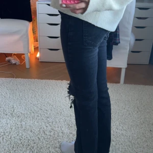 Svarta jeans med slitningar - Snygga svarta jeans med slitningar på knäna. De är i storlek 152. Och de är low waist. Köpt för ca 500kr är från Gina tricot men har gjort hålen själv 