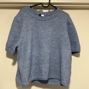 Blå stickad tröja - Säljer en mysig blå stickad tröja med korta ärmar. Perfekt för en avslappnad stil. Tröjan har en rund halsringning och ribbade kanter.