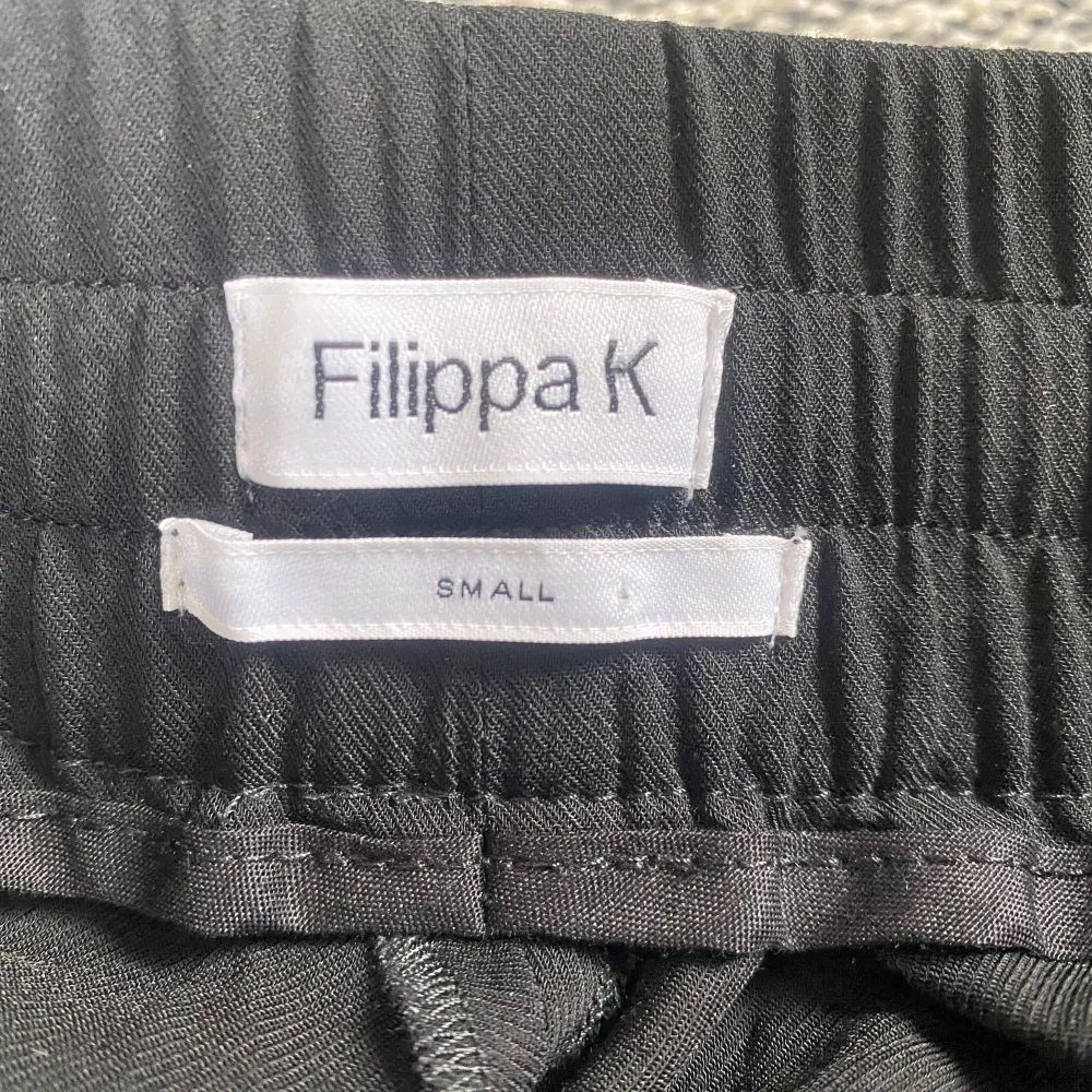 Snygg svart kjol från Filippa K i storlek small. Kjolen har en bekväm resårmidja med knytband och är tillverkad i en mjuk blandning av viskos och elastodien. Perfekt för en stilren look. Ny svart vidare kjol i strl S från Filippa K. Ny, aldrig använd. Mått Midjan: ca 38 cm Total längd: ca 60 cm 96% viskos och 4% elastan Kommer från ett djur och rökfritt hem.. Hameet.