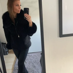 Svart jacka med pälsdetaljer - Snygg svart jacka med pälsdetaljer på krage och ärmslut. Jackan har dragkedja framtill och stora fickor. Perfekt för kyligare dagar. Nypris 2500kr
