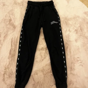 Svarta leggins - Svarta leggins med tryck längs sidorna och text,  elastisk midja. Strl XS