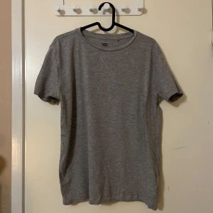Grå t-shirt från 157 - Säljer en enkel och stilren grå t-shirt från 157. Tillverkad i en mjuk blandning av bomull och viskos, perfekt för en avslappnad look. T-shirten har en normal passform och korta ärmar.