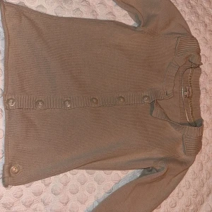 Beige kofta från Cappuccini - Säljer en stilren beige kofta från Cappuccini. Den har långa ärmar och knappar framtill. Perfekt för en avslappnad look. 