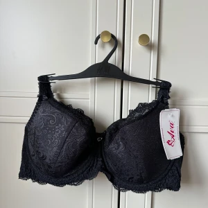 Svart spets-bh från Ava Lingerie - Elegant svart bh från polska märket Ava Lingerie med vackert spetsmönster. Den har en klassisk design med breda axelband för extra stöd och komfort. Perfekt för att känna sig både bekväm och stilfull. Justerbara axelband. Aldrig använd. Ord pris 499kr
